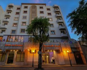 un edificio blanco con un árbol delante en El Oumara Hotel en Túnez