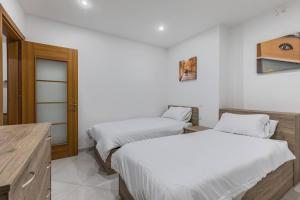 two beds in a room with white walls at Marsaxlokk Fishing Village - Two Bedroom Apartment - 3rd Floor in Marsaxlokk