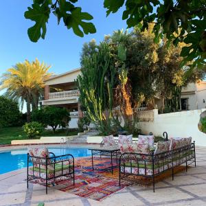 Tiguimi Vacances - Oasis Villas, cadre naturel et vue montagne في أغادير: مجموعة كراسي وطاولة بجانب مسبح