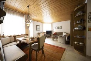 a living room with a wooden ceiling and a table at Chasa Serras - Döpper in Scuol