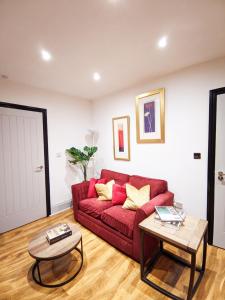 a living room with a red couch and two tables at A&A Luxury Stay Alice in Sunderland