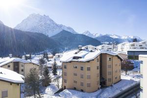 a city with snow covered buildings and mountains at Chasa Serras - Döpper in Scuol