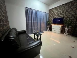 a living room with a black leather couch and a television at Future Hostel Pattaya in Nong Prue