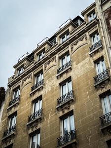 un grand bâtiment en briques avec des fenêtres et des balcons dans l'établissement Hotel de Flore - Montmartre, à Paris