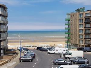 un aparcamiento con coches estacionados junto a la playa en Delphine, en Koksijde