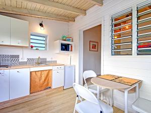 eine Küche mit weißen Schränken sowie einem Tisch und Stühlen in der Unterkunft Appartement Saint-Martin , 2 pièces, 3 personnes - FR-1-734-15 in Saint Martin
