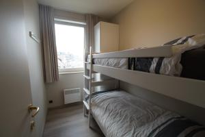 1 dormitorio con 2 literas y ventana en Delphine, en Koksijde