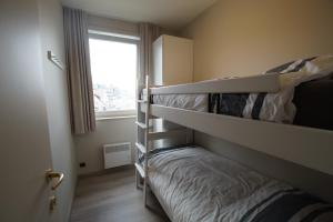 a bedroom with two bunk beds and a window at Delphine in Koksijde