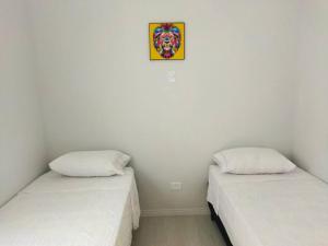 duas camas num quarto com uma fotografia na parede em Kitnet 1 - próximo ao centro de Jacareí em Jacareí