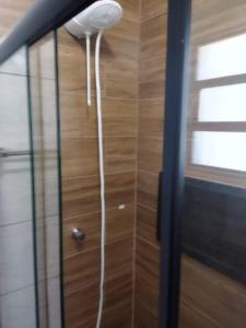 une douche avec un pommeau de douche blanc suspendu à un mur dans l'établissement Kitnet 1 - próximo ao centro de Jacareí, à Jacareí