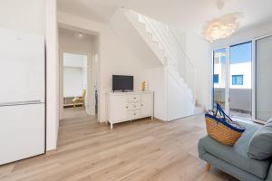 un soggiorno bianco con un divano e una TV di I Tre Golfi - Appartamenti con Terrazzo fino a 800 mt dal mare a San Vito lo Capo