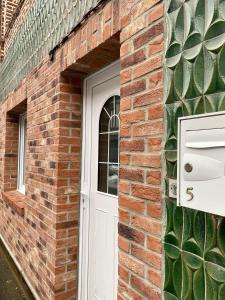 un edificio de ladrillo con una puerta blanca y una ventana en Studio spacieux proche gare et centre ville, en Saint-Amand-les-Eaux