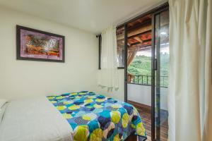 a bedroom with a bed and a large window at Kairí Lodge Natural Reserve in Manizales