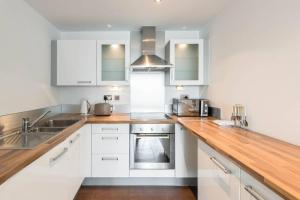 a kitchen with white cabinets and a wooden counter top at Excel Manor in London