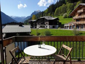 Studio Morzine, 1 pièce, 4 personnes - FR-1-754-57 في مورزين: طاولة مع كأس نبيذ وكرسيين على شرفة