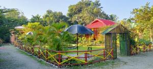 a garden with a fence and an umbrella at Prakriti neerh in Jyoti Gaon