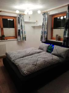 a bed in a bedroom with two windows at Ferienwohnung Thresi Leo in Hart im Zillertal