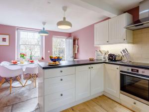 a kitchen with pink walls and white cabinets and a table at 2 Bed in Bath 81298 in Wingfield