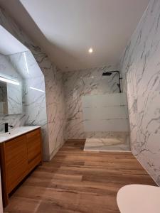 a bathroom with a sink and a shower with marble walls at Appartement Loft haut standing in Douai