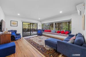 a living room with blue couches and red pillows at Bird Sounds, Rhyll in Rhyll
