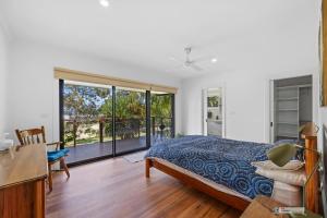 a bedroom with a bed and a sliding glass door at Bird Sounds, Rhyll in Rhyll