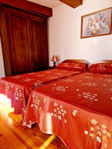 a bedroom with two beds with red covers at Maison paysanne, proche Aubrac in Huparlac