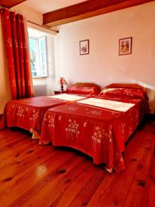 ein Schlafzimmer mit zwei Betten mit roten Decken in der Unterkunft Maison paysanne, proche Aubrac in Huparlac