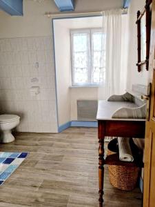 ein Bad mit einem Waschbecken, einem WC und einem Fenster in der Unterkunft Maison paysanne, proche Aubrac in Huparlac
