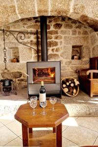 eine Flasche Wein und zwei Gläser auf dem Tisch vor dem Kamin in der Unterkunft Maison paysanne, proche Aubrac in Huparlac