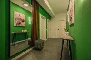 a hallway with green walls and a table and a stool at TheMuseApartament in Alba Iulia