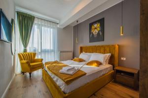 a bedroom with a bed and a yellow chair at TheMuseApartament in Alba Iulia