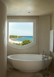 uma banheira na casa de banho com uma janela em Romazzino, A Belmond Hotel, Costa Smeralda em Porto Cervo