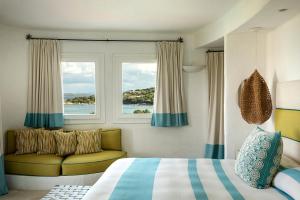 ポルト・チェルボにあるRomazzino, A Belmond Hotel, Costa Smeraldaのベッドルーム1室(ベッド1台、窓、ソファ付)