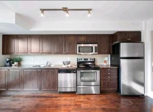 a kitchen with wooden cabinets and stainless steel appliances at CN Tower View with Free Parking, Pool, & Gym by Trains and Buses in Toronto