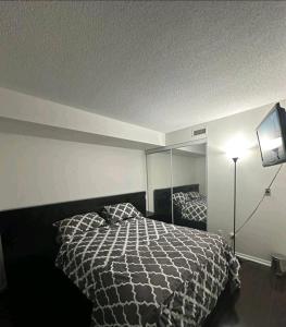 a bedroom with a black and white bed and a tv at CN Tower View with Free Parking, Pool, & Gym by Trains and Buses in Toronto