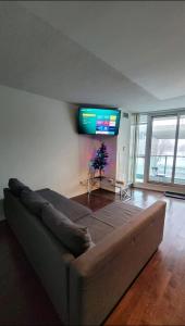 een woonkamer met een bank en een televisie aan de muur bij CN Tower View with Free Parking, Pool, & Gym by Trains and Buses in Toronto
