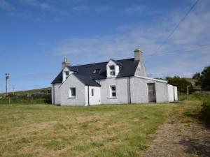 a white house with a black roof in a field at 3 Bed in North Uist 77239 in Sollas