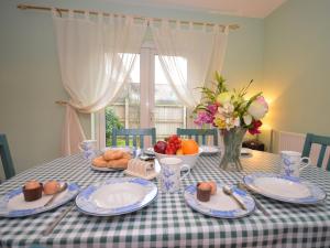 a table with plates of food and a bowl of fruit at 3 bed in Minehead TRINI in Minehead