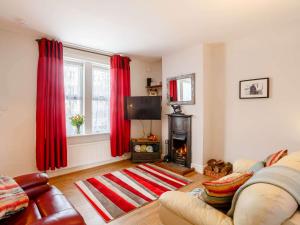 een woonkamer met een open haard en rode gordijnen bij 2 Bed in Kettlewell 87370 in Kettlewell