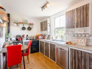 a kitchen with wooden cabinets and a table and red chairs at 2 Bed in Kettlewell 87370 in Kettlewell