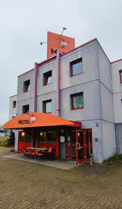 un edificio de motel con mesas y sillas frente a él en Motel 24h Hannover, en Hannover