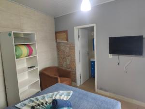 a living room with a bed and a tv and a room at Moradas Vô Ary in Garopaba