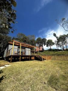 a small house with a porch on a grass field at Chalé Container do Beijo in Campos do Jordão