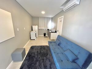 a living room with a blue couch and a kitchen at Hotel Residencial Manaus - Dom Pedro I in Manaus