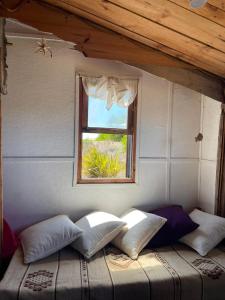 Cama con almohadas en habitación con ventana en Satori, en Barra de Valizas