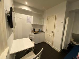 a small kitchen with a white table and a white door at City Center Studio Amsterdam in Amsterdam