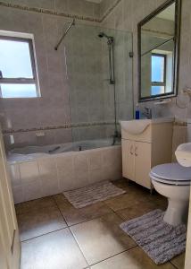 La salle de bains est pourvue d'une baignoire, d'un lavabo et de toilettes. dans l'établissement Kleinmond Panorama Holidays, à Kleinmond