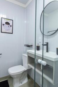 a white bathroom with a toilet and a glass shower at Chalé Container do Beijo in Campos do Jordão