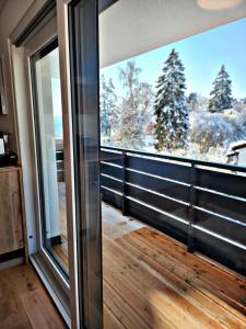 a balcony with a large window with a view of snow covered trees at Lions Place Premium Apartments EXECUTIVE Luxus PENTHOUSE inklusive SPA in Heidenheim an der Brenz