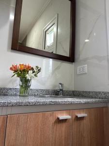 a bathroom with a sink and a mirror and flowers at Fitz Roy Hoster&iacute;a de Monta&ntilde;a - El Chalt&eacute;n in El Chalten